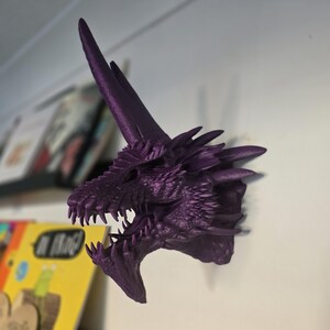 May include: Purple 3D printed dragon head wall mount with a sharp, pointed horn and an open mouth with sharp teeth.