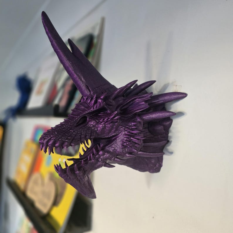 May include: Purple dragon head wall mount with a textured surface and sharp teeth. The dragon has a long, pointed horn on its head.