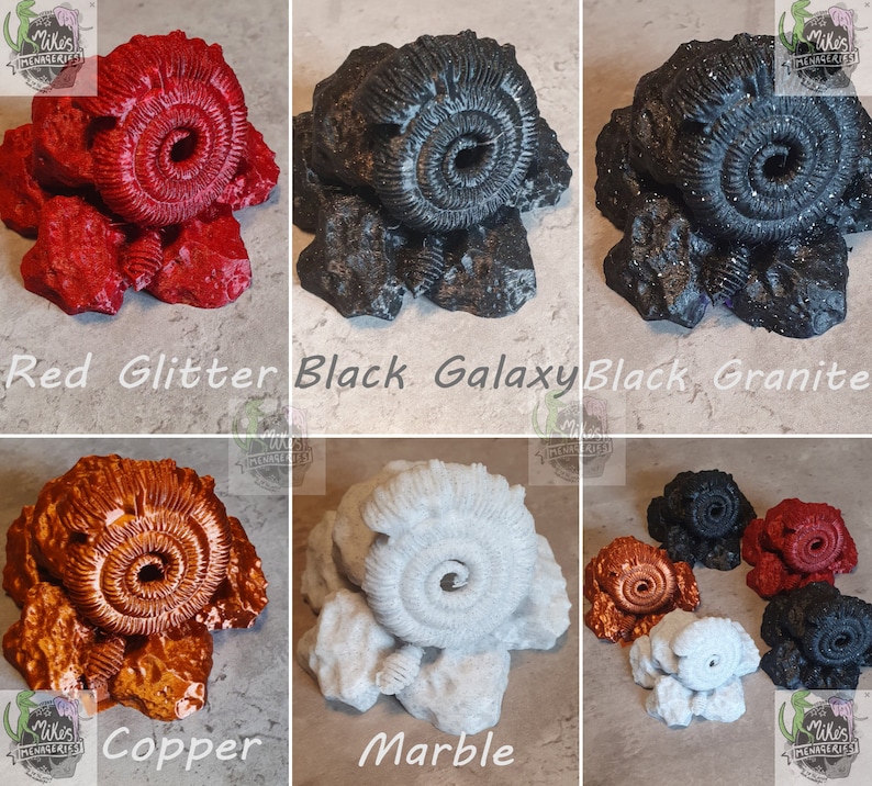 May include: Ten different colored ammonite fossil replicas. The colors include red glitter, black galaxy, black granite, copper, marble, white, black, red, and orange. The ammonites are all the same size and shape, and they are all sitting on a white background.