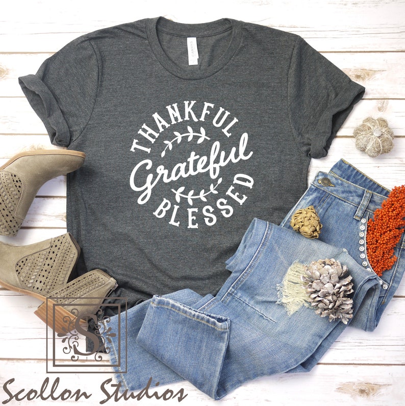 May include: A dark gray t-shirt with a white circle graphic that says "Thankful Grateful Blessed" with a leafy design.