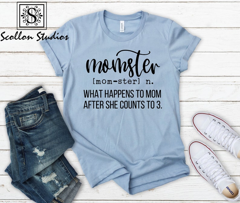 May include: A light blue t-shirt with black text that reads "momster [mom-ster] n. WHAT HAPPENS TO MOM AFTER SHE COUNTS TO 3."