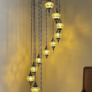 Op de afbeelding: Een spiraalvormige kroonluchter met 10 glazen bollen, elk met een mozaïekpatroon. De kroonluchter is gemaakt van metaal en heeft een zwarte afwerking. De bollen worden verlicht met warm wit licht. De kroonluchter is 86 inch hoog en 25 inch breed. De bollen zijn 5 inch breed en 4 inch hoog. Turkish Lights. Net