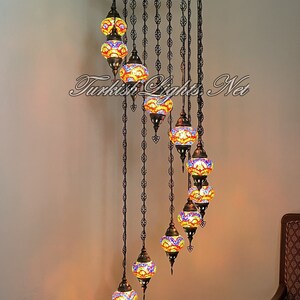 Op de afbeelding: Een spiraalvormige kroonluchter met 10 kleurrijke glazen bollen. De kroonluchter is 86 inch hoog en 25 inch breed. Elke bol is 5 inch breed en 4 inch hoog. De kroonluchter is gemaakt van metaal en heeft een zwarte afwerking.