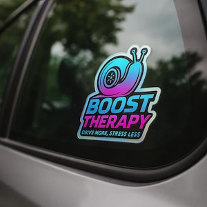 May include: A holographic sticker with a snail and a turbocharger design. The sticker has the words "BOOST THERAPY" in a bold font, with the tagline "DRIVE MORE, STRESS LESS". The snail is blue and purple.