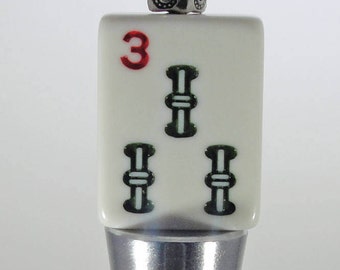 May include: A silver bottle stopper with a white ceramic top featuring a red number "3" and three green bamboo symbols.