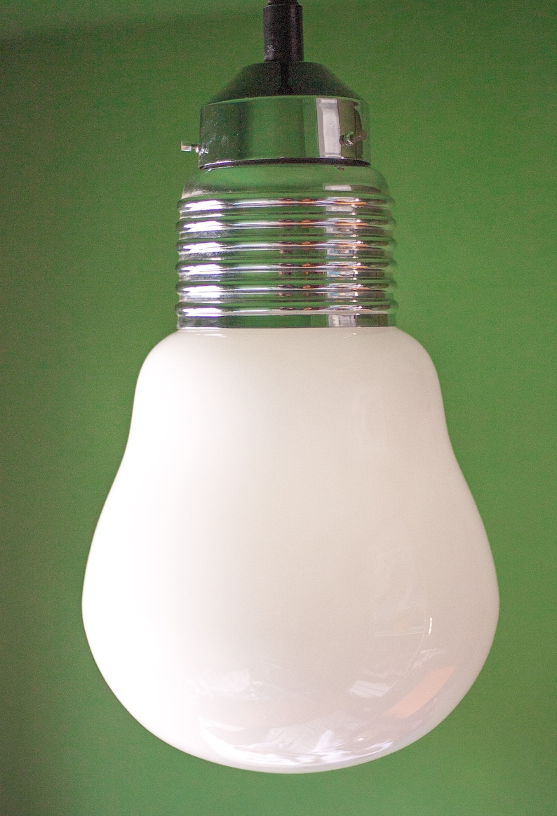 May include: A white glass light bulb with a chrome metal base and a black cord hanging from the ceiling.