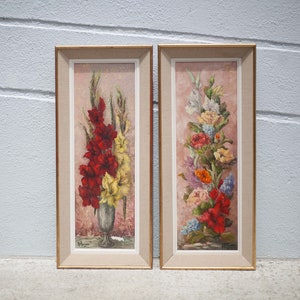 May include: A pair of framed floral paintings with a pink background. The paintings feature a bouquet of red, yellow, and white flowers in a vase.