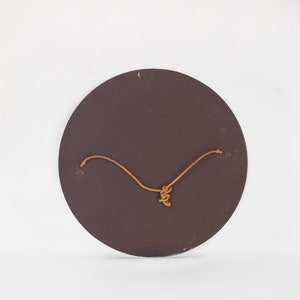 May include: The back of a round, brown, wooden mirror with a string attached for hanging.