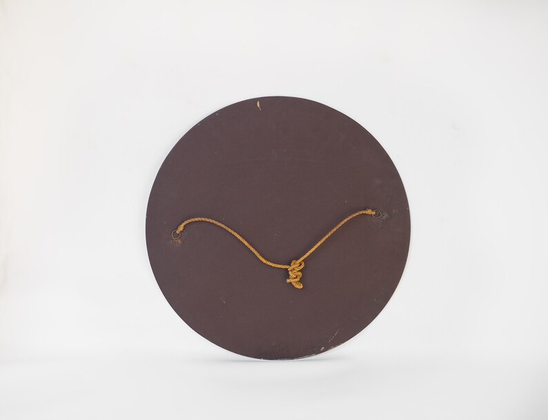 May include: The back of a round, brown, wooden mirror with a string attached for hanging.
