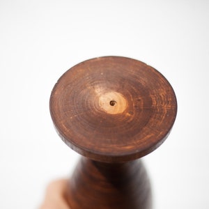 Peut inclure: Un vase en bois brun fonc&eacute; avec une base ronde et un trou au centre. Le vase est en bois et a une finition naturelle.
