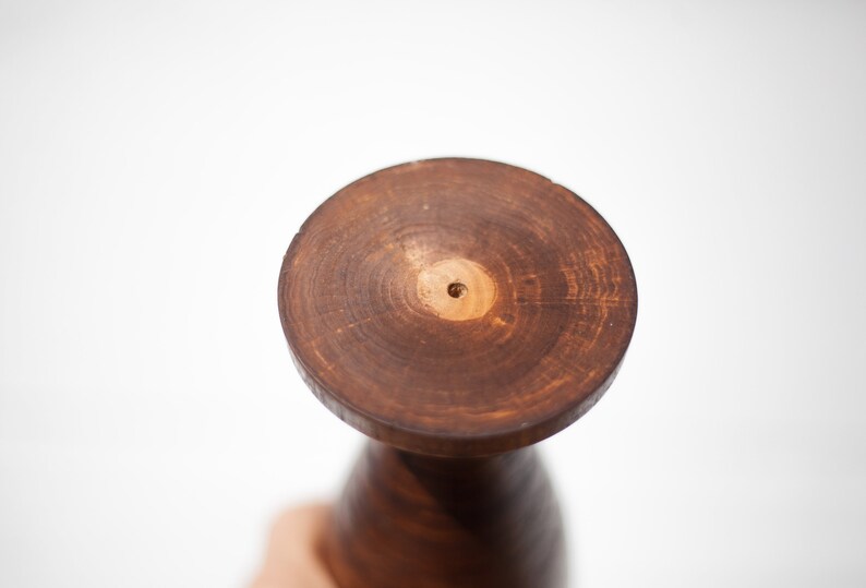 Peut inclure: Un vase en bois brun fonc&eacute; avec une base ronde et un trou au centre. Le vase est en bois et a une finition naturelle.