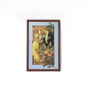 May include: A rectangular wall art piece in a dark brown wooden frame featuring a vintage-style illustration of a person in a long light green dress and a person in a black suit standing together amidst green foliage and orange flowers.