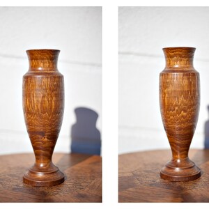 Peut inclure: Un vase en bois avec une finition en bois naturel brun. Le vase a un corps arrondi et une base &eacute;vas&eacute;e.