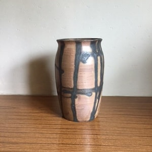 Peut inclure: Un vase en céramique brun avec des marques abstraites noires. Le vase a un corps arrondi et une ouverture légèrement évasée.