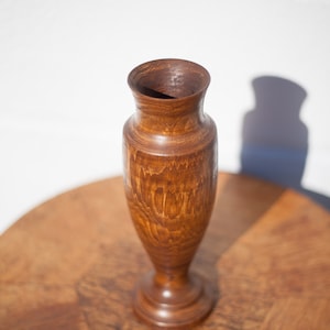 Peut inclure: Un vase en bois avec une finition teint&eacute;e brune. Le vase a une base arrondie et un col &eacute;troit.