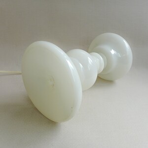 May include: White glass table lamp with a rounded base and a wide, flat top. The lamp has a simple, modern design.