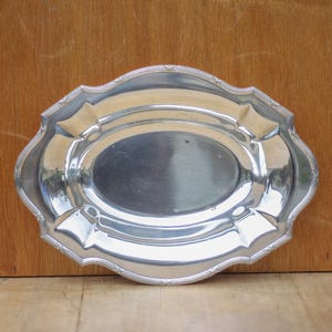 May include: A silver oval serving tray with a decorative, scalloped edge.