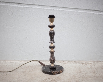 May include: A black and gold marble table lamp with a black lampshade. The lamp has a round base and a tall, slender stem.