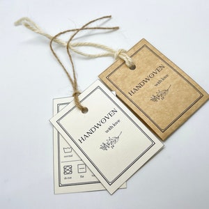 May include: Two brown and white gift tags with black text and a small floral design. The text on the tags reads "Handwoven with love".