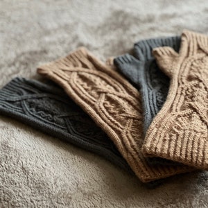 May include: Three pairs of knitted arm warmers in a cable knit pattern. Two pairs are brown and one pair is gray.