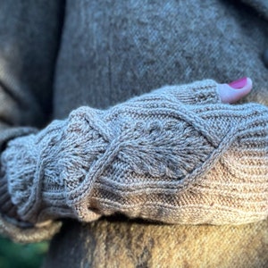May include: A pair of brown knitted fingerless gloves with a cable knit pattern.