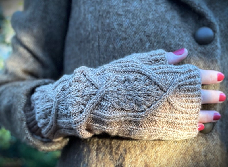 May include: A pair of brown knitted fingerless gloves with a cable knit pattern.