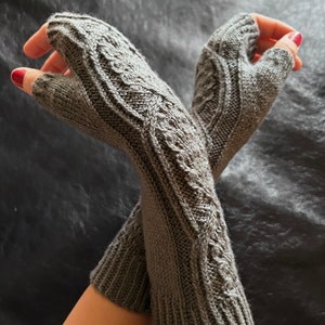 May include: A pair of gray fingerless gloves with a cable knit pattern.