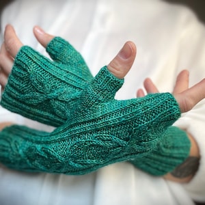 May include: A pair of teal blue fingerless gloves with a cable knit pattern.