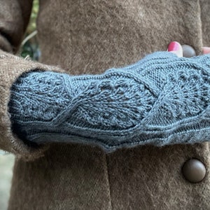 May include: A pair of blue knitted fingerless gloves with a cable knit pattern.