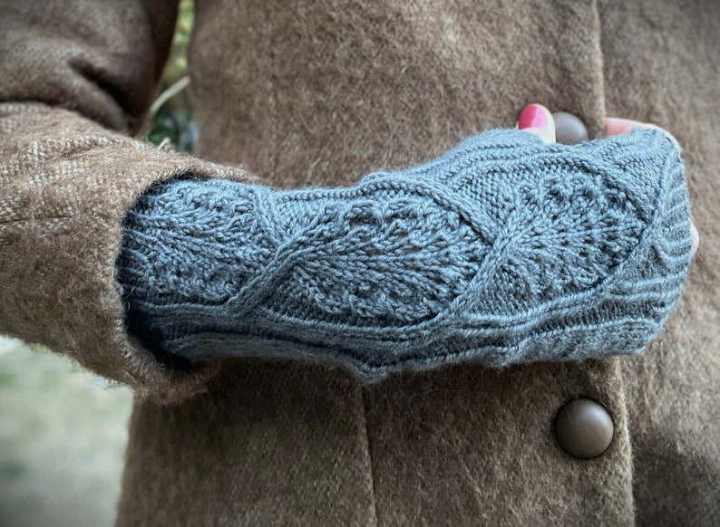 May include: A pair of blue knitted fingerless gloves with a cable knit pattern.
