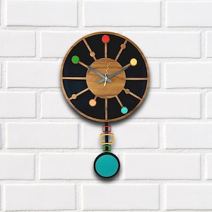 May include: A black and wood clock with a pendulum. The clock face has a black background with a wood center and five colorful circles around the edge. The pendulum is made of wood and has four colorful squares.