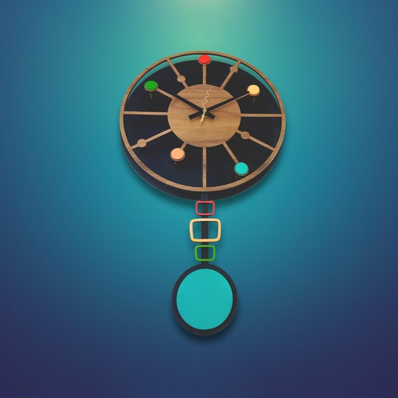 A handmade wood pendulum ball wall clock that looks like it escaped from a 1957 design exhibition — kinetic, sculptural, and actually functional.