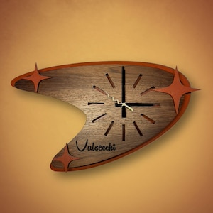 May include: A brown wooden clock with a boomerang shape and a red border. The clock face has black hour and minute hands and a white second hand. The clock face also has a black inscription that reads "Valsecchi". The clock has three red star-shaped accents.
