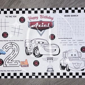 May include: A rectangular activity placemat featuring a black and white checkered border. The center displays a Happy Birthday Aziel graphic with Lightning McQueen, a word search, a tic tac toe grid, a number two maze, and a Mater illustration.