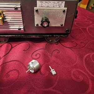 May include: A close-up of a silver metal knob with a black center. The knob is attached to a silver metal panel with a label that reads "SIDE MM PN SIDE MM PN A 3 150 C 2 300/500 A 100 18 C 3 300/600".