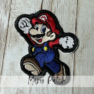 May include: Embroidered Mario patch featuring the iconic video game character in a dynamic pose. The patch showcases Mario in his signature red hat, blue overalls, and brown shoes, outlined in black. The text "Mario Patch" is displayed below.