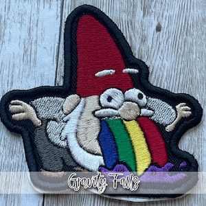 May include: Embroidered patch featuring a cartoon character with a red hat, white beard, and rainbow vomit. The patch has the text "Gravity Falls" in a script font and is outlined in black.