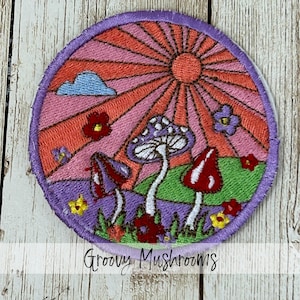 May include: Embroidered patch featuring a colorful mushroom scene with a sunburst background. The patch includes purple, red, and white mushrooms, flowers, and the text "Groovy Mushrooms". The patch is round with a purple border.