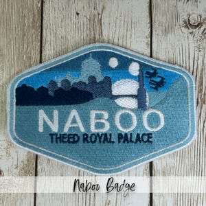 May include: Embroidered patch featuring a landscape scene with the text "NABOO" and "THEED ROYAL PALACE" in white. The patch has a blue and white color scheme with a light blue border. The bottom of the image has the text "Naboo Badge".
