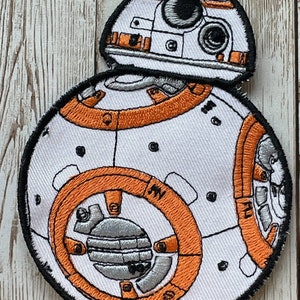 May include: Embroidered patch of BB-8, a white and orange Star Wars droid with a black outline. The droid has a round body with a smaller dome on top.