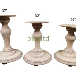 May include: Three wooden pedestal bases in different sizes: 37 inches, 32 inches, and 29 inches. The bases are made of light wood and have a simple, elegant design.
