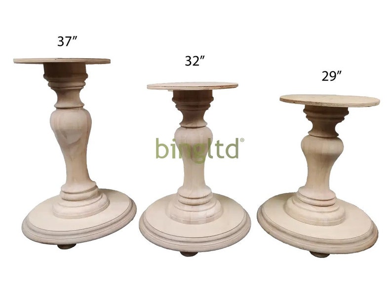 May include: Three wooden pedestal bases in different sizes: 37 inches, 32 inches, and 29 inches. The bases are made of light wood and have a simple, elegant design.