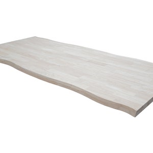 May include: A light wood table top with a live edge design. The table top is smooth and has a natural wood grain.