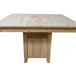 May include: A light wood square dining table with a leaf extension. The table has a simple design with a rectangular base and a smooth top.