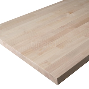 May include: Close-up of a light-colored wooden butcher block countertop. The wood grain is visible, and the surface is made of rectangular pieces of wood joined together. The countertop is rectangular and has a smooth, finished edge.