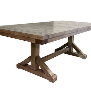 May include: A rustic wooden dining table with a trestle base and a gray wood finish. The table has a rectangular top and is made of solid wood.