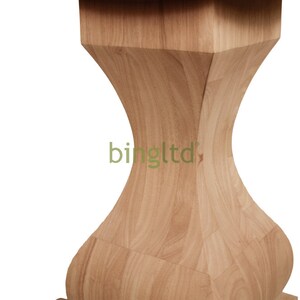 Puede incluir: Una mesa de madera de color claro con una parte superior redonda y una base de forma &uacute;nica. La base tiene un dise&ntilde;o en forma de reloj de arena, con una parte superior e inferior cuadradas. La mesa es de madera clara.