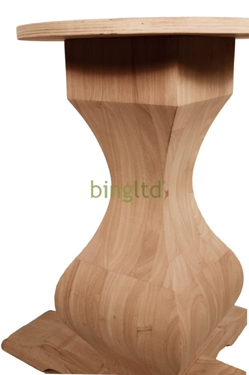 Puede incluir: Una mesa de madera de color claro con una parte superior redonda y una base de forma &uacute;nica. La base tiene un dise&ntilde;o en forma de reloj de arena, con una parte superior e inferior cuadradas. La mesa es de madera clara.