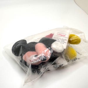 Pu&ograve; includere: Un sacchetto di plastica trasparente contenente diverse parti in peluche di Topolino. Le parti includono orecchie nere, viso e mani rosa, guanti bianchi e cerchi gialli. Il sacchetto &egrave; sigillato.