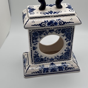 May include: A white ceramic decorative lantern with blue floral patterns and a dark blue handle. The lantern features a square shape with a circular opening and intricate hand-painted designs, showcasing a classic, elegant style.
